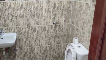 Ein kleines Badezimmer mit Toilette, Waschbecken und Fliesen.