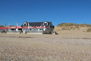 A beachside building with a cafe, bar, and shop. - Sandunes 1 (Rye)