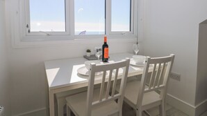 Ein Essbereich mit Tisch, Stühlen, einer Weinflasche und einem Glas.