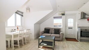 Eine moderne Loft-Wohnung mit Essbereich, einer Couch, einer Küche und einem großen Fenster, das für natürliches Licht sorgt.