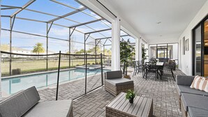A covered outdoor area with a pool, seating, and a view of the surrounding landscape. - Last Minute Disney! Private Pool, Hot Tub, Game Room & Themed Bedrooms. Book Now! #112977 (Orlando)