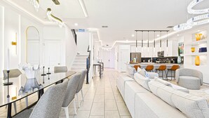 A modern interior with a dining area, a sofa, and a kitchen. - Last Minute Disney! Private Pool, Hot Tub, Game Room & Themed Bedrooms. Book Now! #112977 (Orlando)