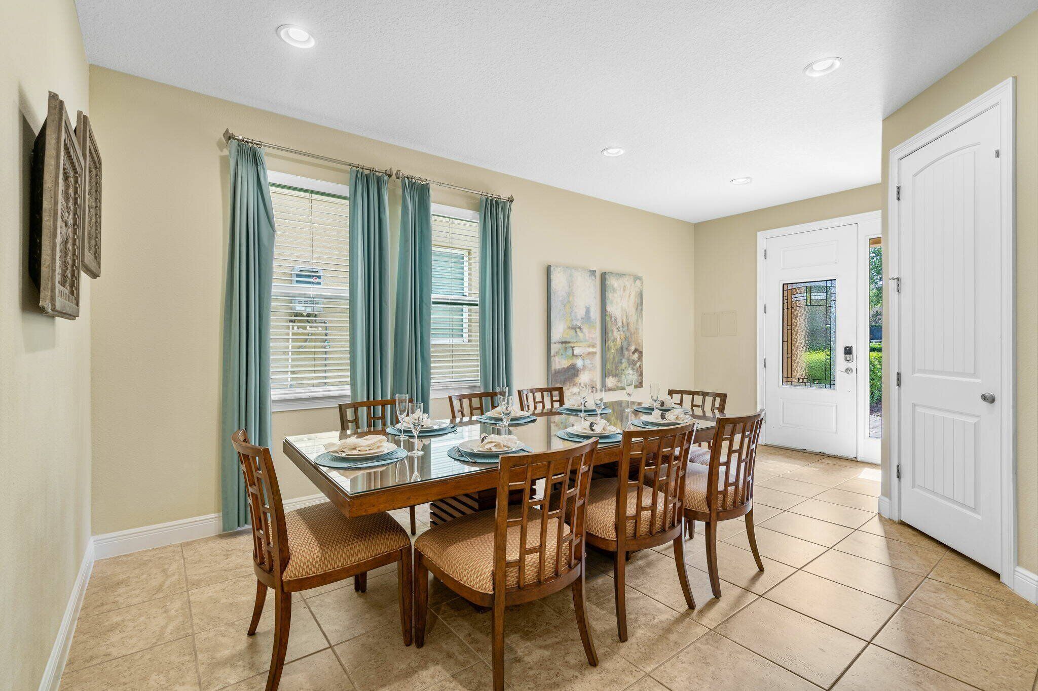 A dining room with a rectangular table set for six, surrounded by wooden chairs with woven seats.