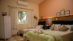 Een hotelkamer met twee bedden, een koelkast, een raam met gordijnen en foto's aan de muur.