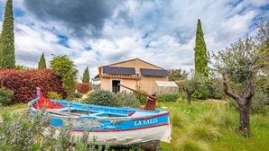A boat named "LA SALIS" docked in a lush garden with a house in the background.