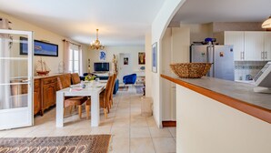 A spacious kitchen with white cabinets, a refrigerator, and a dining area with a table and chairs.