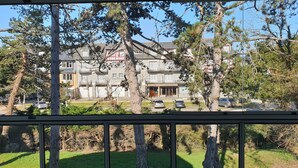 A residential building with multiple balconies, a lawn, and parked cars.