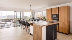 A modern kitchen with a large island, wooden cabinets, and a view of the outdoors.