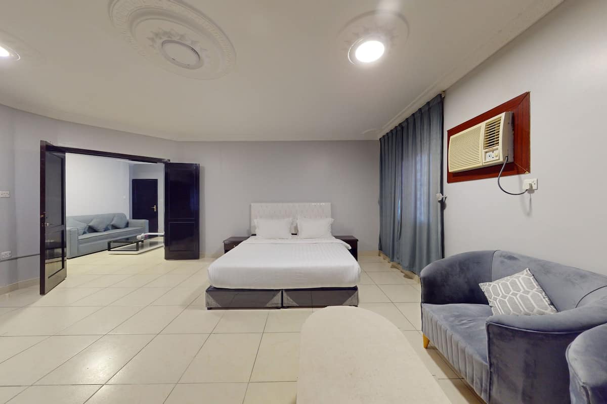 A modern bedroom with a large bed, a sofa, and a TV.