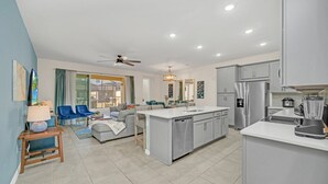 Una cocina moderna con una isla central, electrodomésticos de acero inoxidable y un comedor con sofá y sillas.