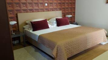 A neatly made bed with a beige bedspread and two pillows, a bedside lamp, and a nightstand.