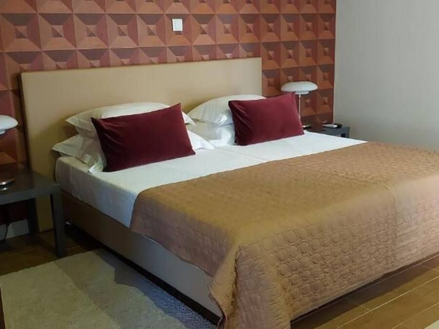 A neatly made bed with a beige bedspread and two pillows, a bedside lamp, and a nightstand.