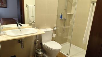 Un baño con lavabo, inodoro y ducha con mampara de vidrio.