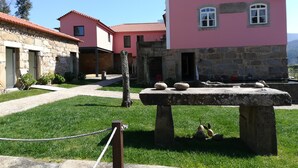 A courtyard with stone buildings, a stone table with sheep, and a rope barrier. - Quinta de Anterronde (Arouca)