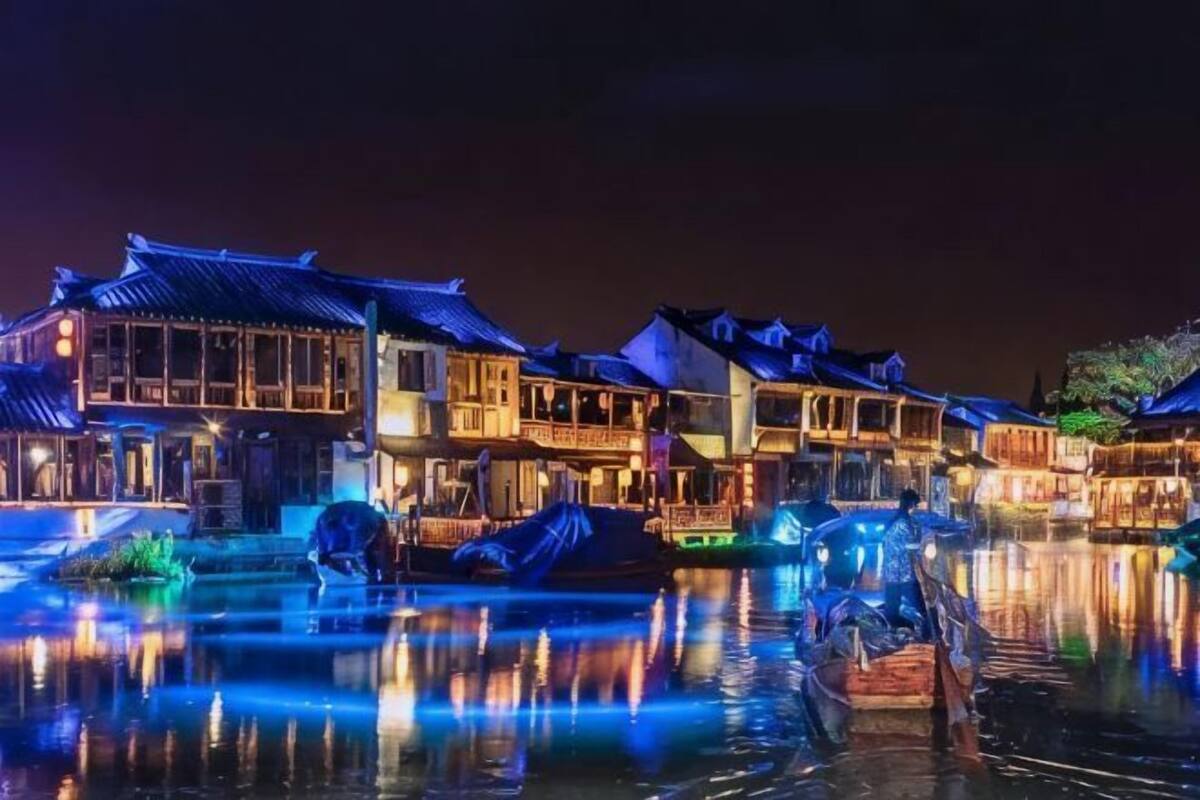 A traditional building with a waterway in front, boats docked, and a person in a boat.