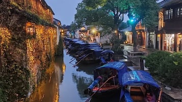 A canal lined with traditional boats and buildings, suggesting a historic or cultural setting.