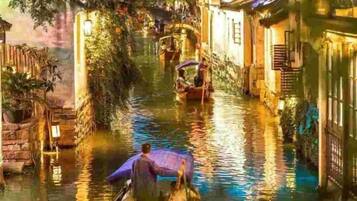 A narrow waterway with boats, traditional buildings, and a bridge.
