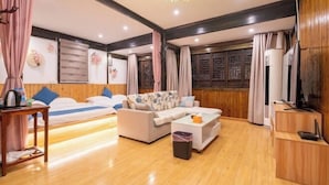 A hotel room with a sofa, a small table, a TV, and a wooden floor. - Zhouzhuang Qingfeng Mingyuelou Boutique Inn (Kunshan)