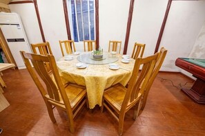 Un comedor con una mesa redonda, sillas de madera y un adorno central.