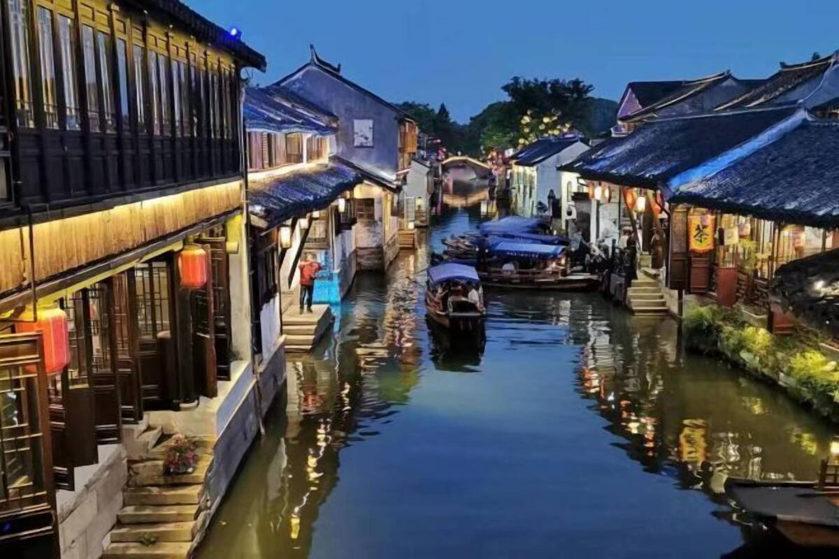 A narrow waterway flanked by traditional buildings with wooden railings and a boat docked in the center.
