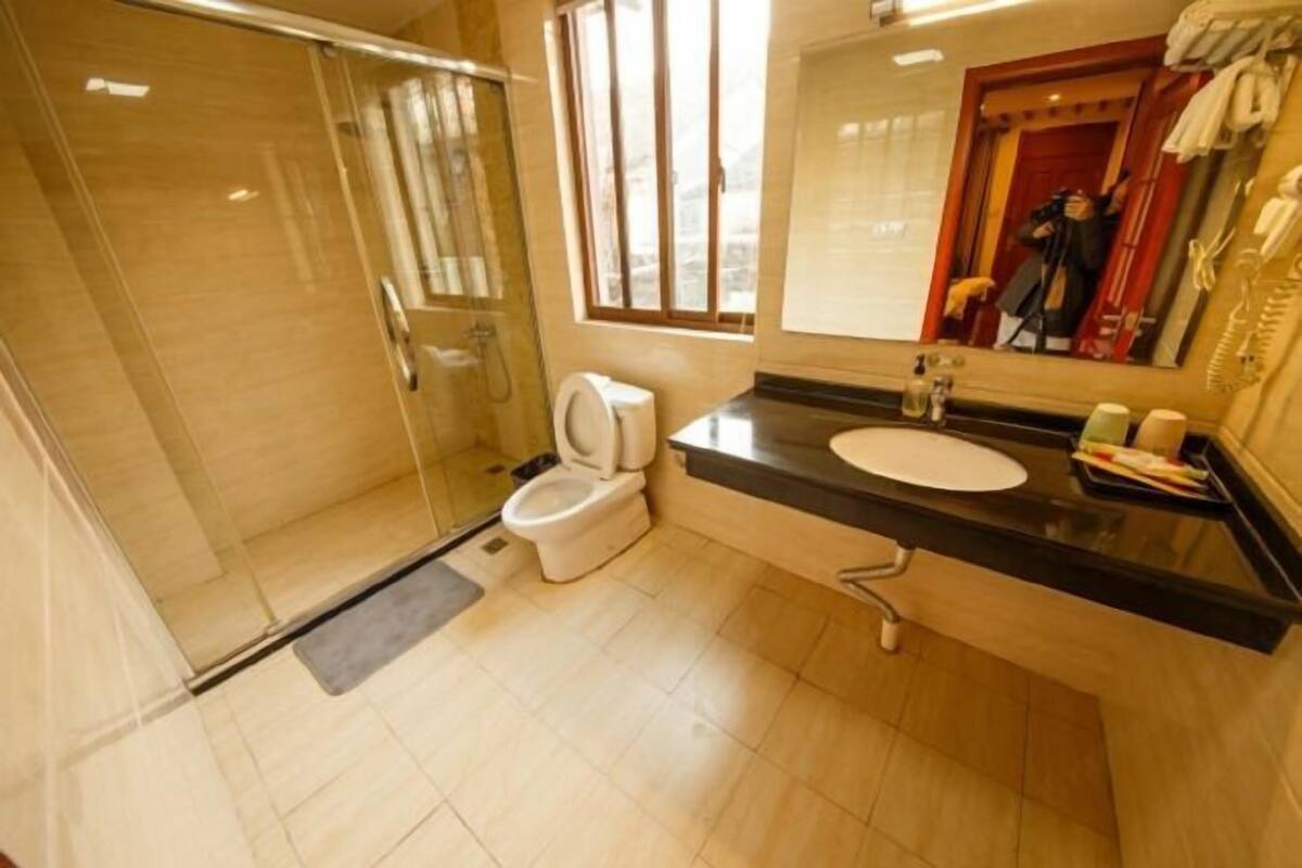 A bathroom with a glass-enclosed shower, a toilet, a sink, and a mirror.