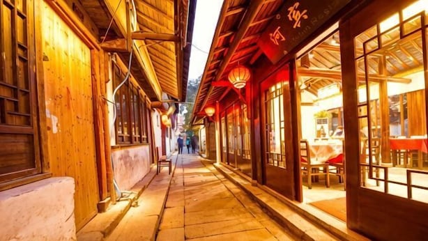 A narrow alleyway with traditional wooden buildings, a bench, and a table with chairs outside a restaurant. - Zhouzhuang Qingfeng Mingyuelou Boutique Inn (Kunshan)