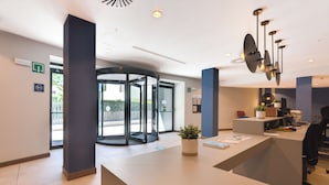 A modern reception area with a revolving door, a reception desk, and a potted plant.