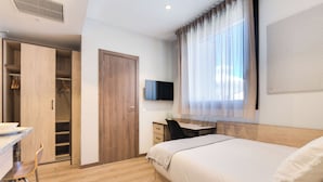 A bedroom with a bed, a desk, a chair, a TV, and a wardrobe.