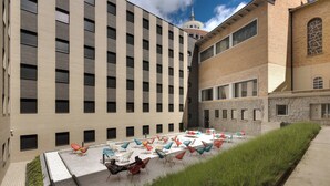 A courtyard with outdoor seating and a building with a tower.
