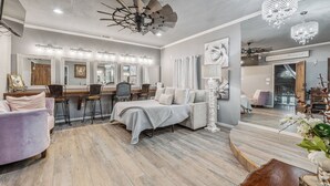 Un dormitorio moderno con una cama grande, un tocador con espejos y una zona de estar con sofá y sillones.