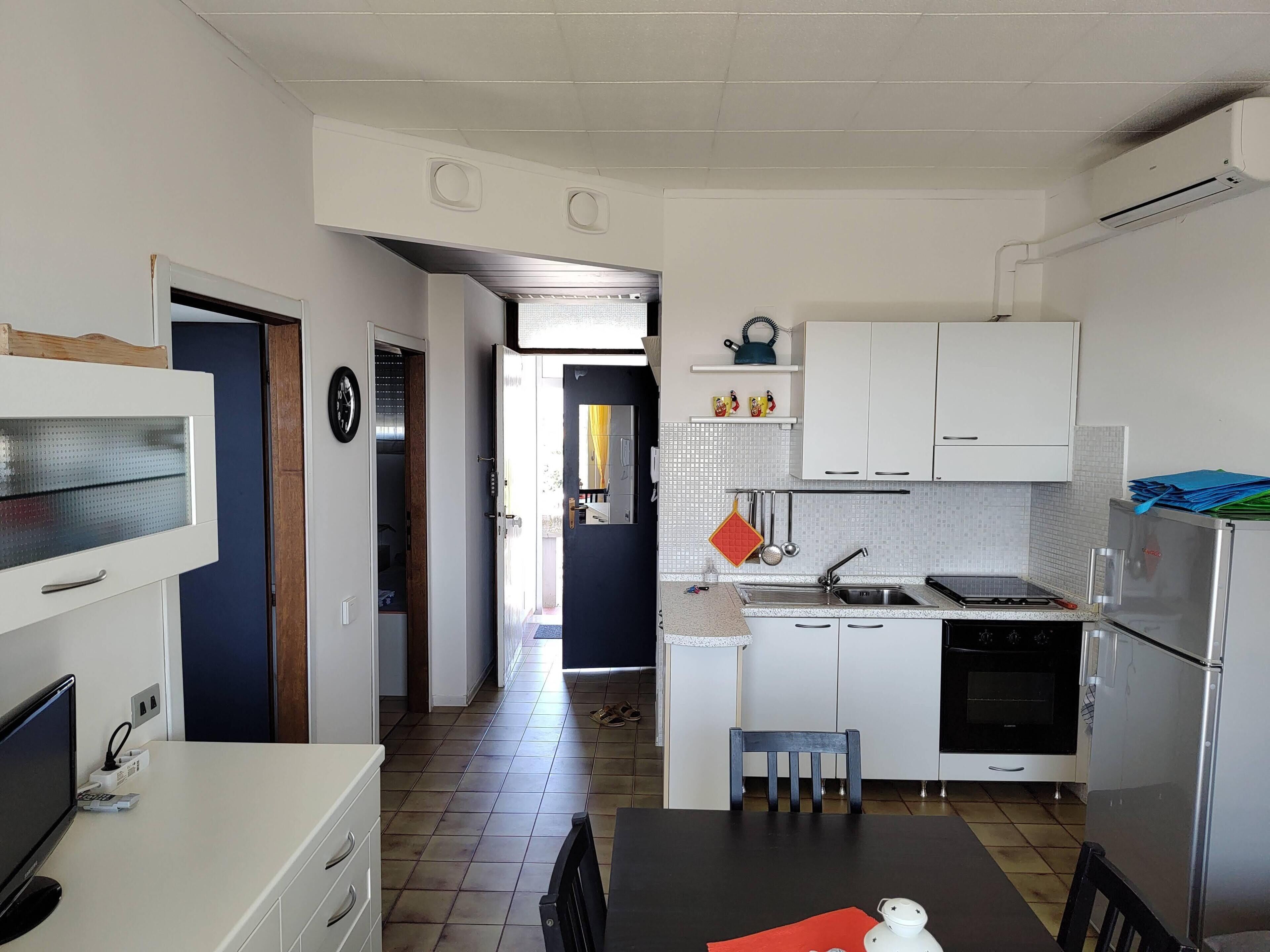 Een kleine keuken met een eethoek, een koelkast, een fornuis en een spoelbak.