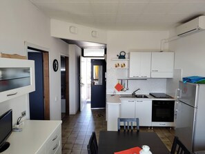 A compact kitchen with a dining area, a refrigerator, a stove, and a sink.