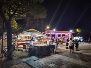 Un mercado nocturno al aire libre con puestos y un escenario.