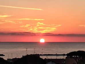 Un atardecer sobre un cuerpo de agua con una costa lejana.
