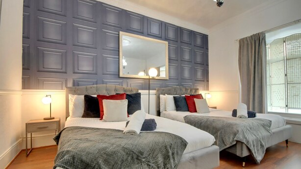 Une chambre double avec deux lits, un grand miroir et une fenêtre avec des rideaux.