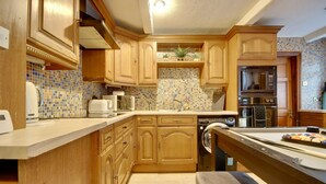 Une cuisine avec des meubles en bois, un pare-feu en carrelage, un four à micro-ondes et un lave-vaisselle.