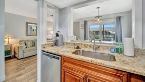 Una cocina moderna con una isla grande, encimera de granito y lavavajillas empotrado.