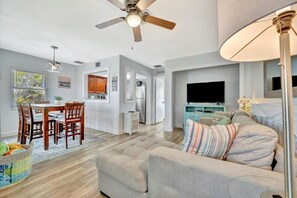 A modern living room with a sofa, TV, and ceiling fan.