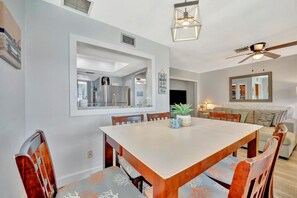 A dining area with a large table, chairs, and a ceiling fan.
