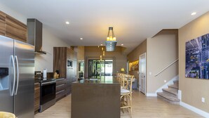 A modern kitchen with a central island, stainless steel appliances, and a wooden accent wall.