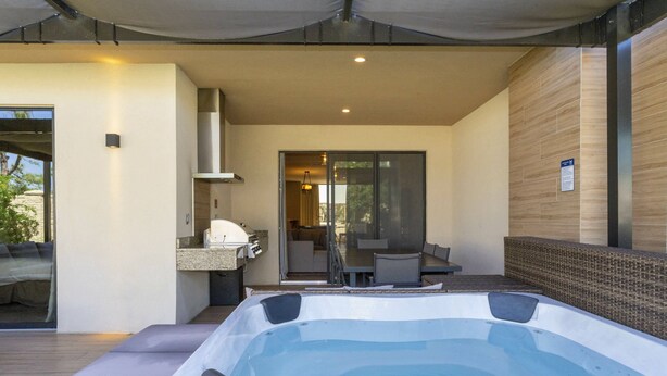 A modern outdoor hot tub area with a glass door leading to a patio.