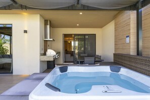 A modern outdoor hot tub area with a glass door leading to a patio.