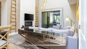 A modern living room with a glass coffee table, white sofa, and a TV mounted on the wall.