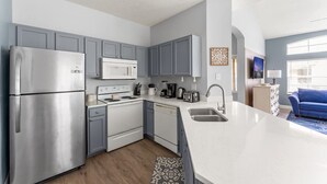 Una cocina moderna con armarios grises, electrodomésticos de acero inoxidable y una isla grande con un fregadero.