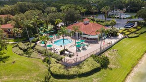 Vista aérea de un resort con piscina, áreas de descanso y un jardín ajardinado.