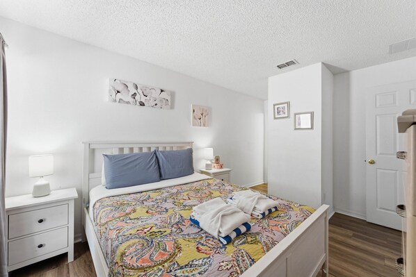 A neatly arranged bedroom with a bed, a bedside table with a lamp, and a nightstand.
