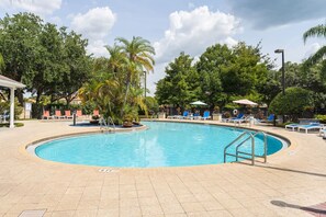A swimming pool with a circular shape, surrounded by lounge chairs and palm trees. - Welcoming 4 BR Sleeps 10 Guests Wl2901 (Kissimmee)