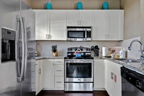 A modern kitchen with stainless steel appliances, white cabinets, and a granite countertop. - Welcoming 4 BR Sleeps 10 Guests Wl2901 (Kissimmee)