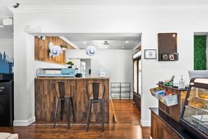 Une cuisine moderne avec un comptoir en bois, deux tabourets de bar et un espace dédié à la préparation des sushis.