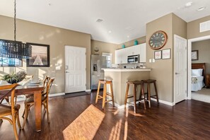 A modern kitchen with a central island, wooden bar stools, and a dining area with a table and chairs. - Welcoming 4 BR Sleeps 10 Guests Wl2901 (Kissimmee)